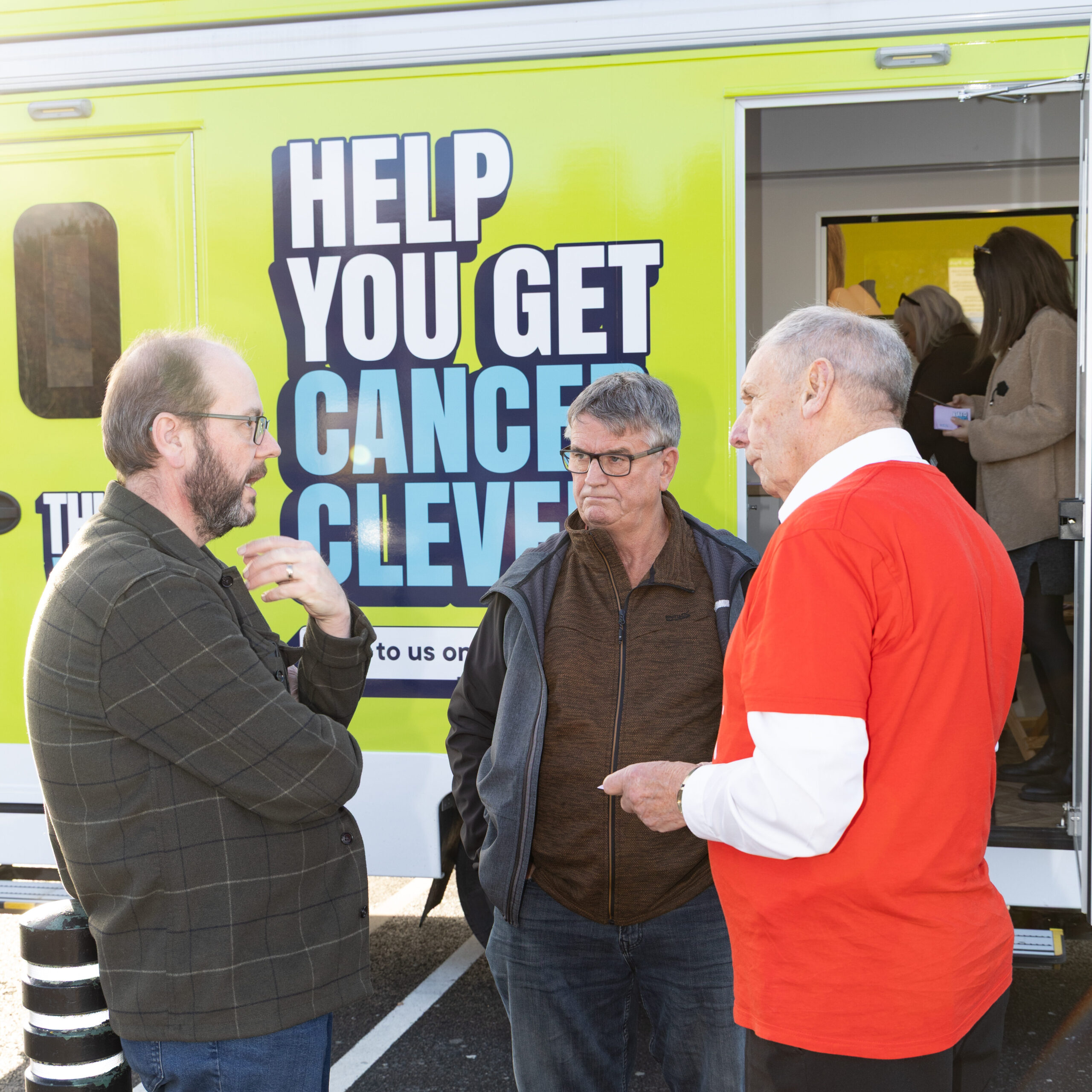 A group of people talking next to the van